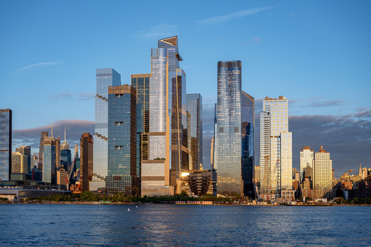 Modern architecture of Hudson Yards skyline in New York. View of The Vessel, Edge, and modern glass skyscrapers at Hudson Yards district during golden hour sunset.