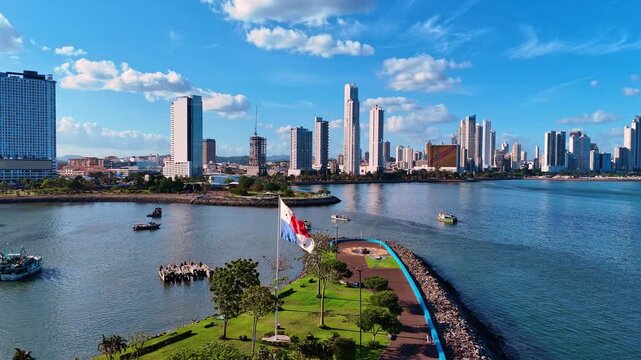 Flag of the Republic of Panama flapping in the wind. Waterscape with boats and high-rise skyline in the backdrop.