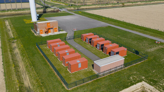 Drone view of wind turbines and a battery storage facility distributing renewable energy, supporting grid balance, clean power infrastructure, and sustainable electricity supply.