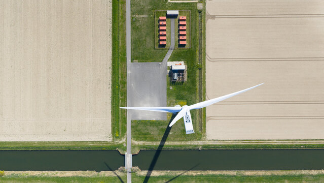 Drone view of wind turbines and a battery storage facility distributing renewable energy, supporting grid balance, clean power infrastructure, and sustainable electricity supply.