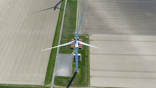 Aerial view of Energiepark Haringvliet Zuid with a large wind turbine casting a long shadow over agricultural fields and technical infrastructure Middelharnis, South Holland, Netherlands.