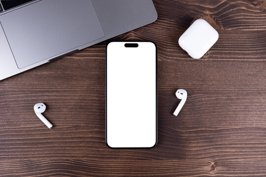 mockup iPhone smartphone with png transparent empty screen blank, template on a wooden table with AirPods headphones, notebook. Batumi, Georgia - March 17, 2026