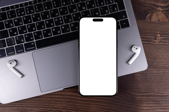 mockup iPhone smartphone with png transparent empty screen blank, template on a wooden table with notebook, AirPods headphones. Batumi, Georgia - March 17, 2026