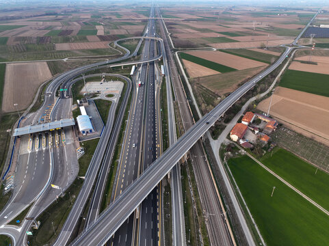 Aerial view of the Autostrada Torino Milano interchange and toll plaza with surrounding agricultural fields and railway tracks in Borgo d'Ale, Piedmont, Italy.