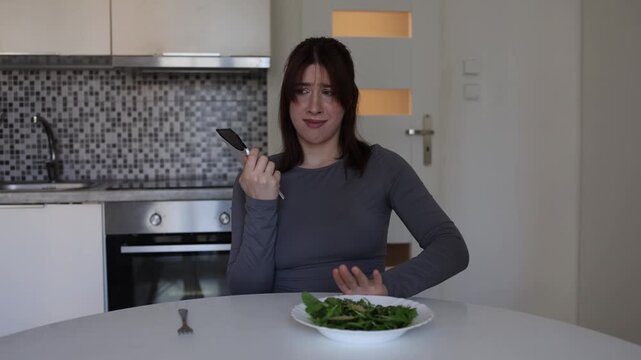 Young woman rejects healthy salad and chooses sweet chocolate unable to control sugar cravings or continue limiting herself with strict diet rules at home