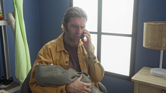 Man holding baby, hand cradling infant and phone to ear in a building nursery; concerned tenderness.