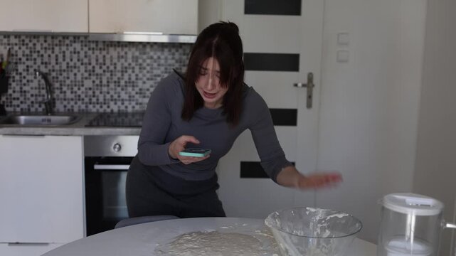 Young woman yells at AI on her phone after terrible cooking advice ruins dough turning a home kitchen into a messy scene about blind tech trust and real life frustrations