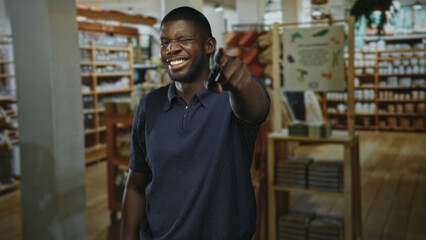 Obraz premium Man points finger at camera showing his hand and smile in a building, close and direct gesture of invitation; friendly joyful welcome.