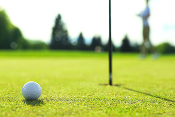 Obraz premium Woman playing golf at green course, focus on ball. Space for text
