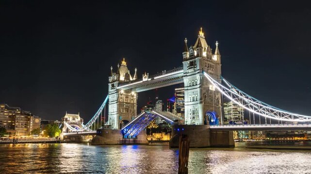 Tower bridge opening at night with illuminated city skyline background showing iconic london cityscape architecture during dark evening time lapse video clip.
