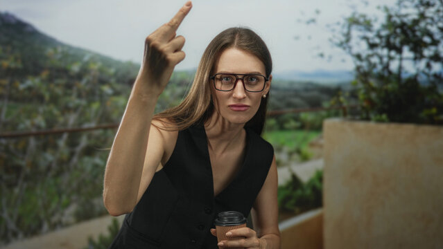 Woman in black vest raises middle finger toward camera while holding a takeaway coffee cup on building terrace with green foliage; defiance.