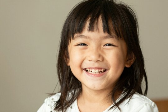 Child laughing with missing tooth in neutral background