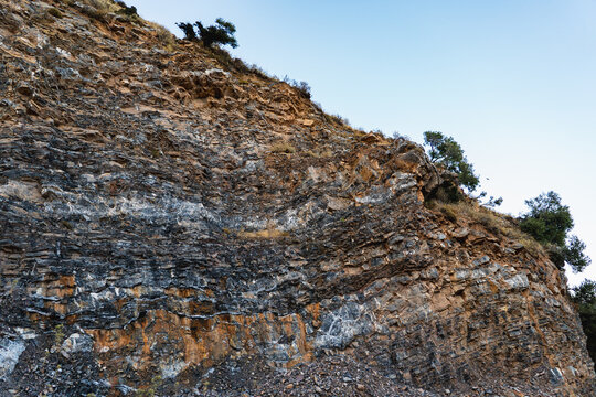 landscape of a mountain slope with sparse vegetation and layers of limestone rocks