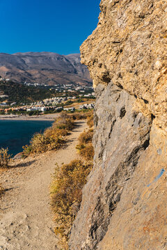 a narrow path along the sea by a steep cliff wall