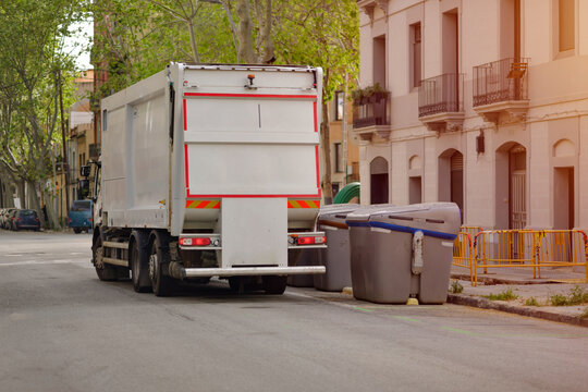 White Garbage Truck Collecting Trash Bins on City Street