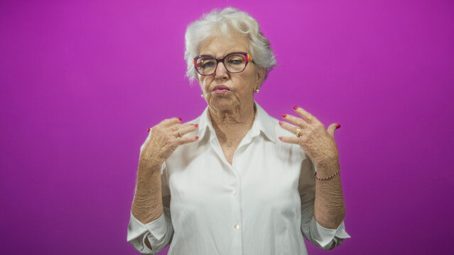 Older woman raises hands palms out showing painted fingernails in a studio portrait; exasperation wit.