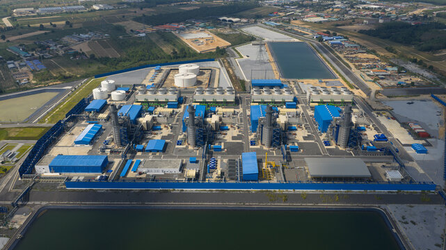 Aerial view of the Gulf Pluak Daeng Power Plant complex with its industrial buildings, cooling towers, and storage tanks under a clear sky in Map Yang Phon, Rayong, Thailand.