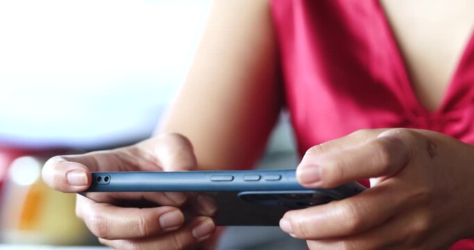 Woman holding smartphone, playing games or typing messages. Everyday mobile use, communication and modern technology concept