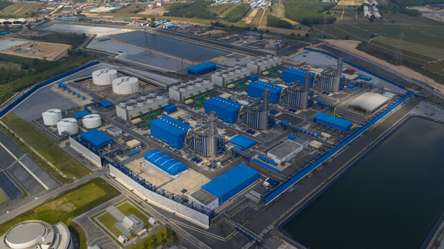 Aerial view of the Gulf Pluak Daeng Power Plant with its blue industrial buildings, white storage tanks, and cooling towers in Map Yang Phon, Rayong, Thailand.