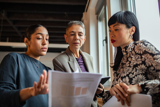 Three businesswomen reviewing documents in modern office