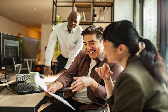 Colleagues reviewing documents on laptop in modern office