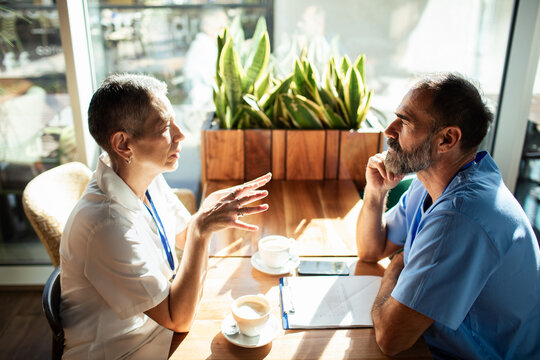 Two healthcare professionals discussing patient care over coffee in a cafe