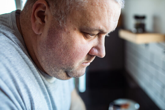 Middle-aged man looking down in home kitchen