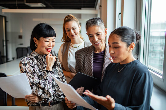 Diverse businesswomen collaborating on documents in modern office