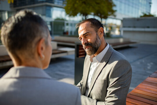 Business colleagues in serious conversation at outdoor office plaza