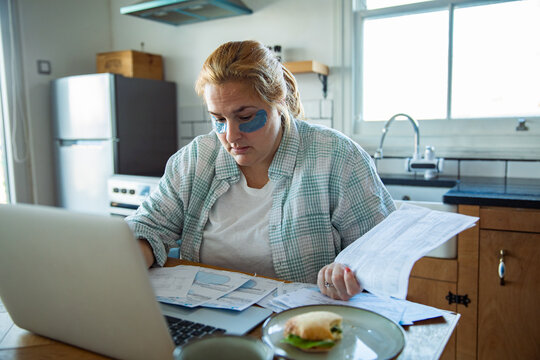 Tired woman paying household bills at kitchen table