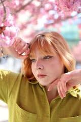 Beautiful young girl posing near blossoming sakura tree outdoors © New Africa