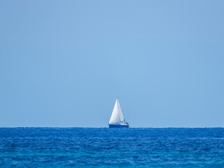 Single Sailboat on Blue Sea Under Clear Sky © Ion B