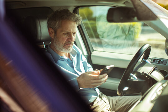 Middle-aged man using smartphone in car