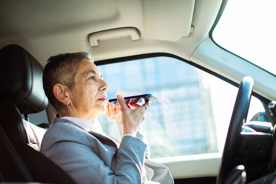 Senior businesswoman using voice assistant in car