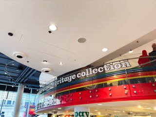 Naklejka premium Shoppers at colorful modern retail interior with heritage collection display and pay here counter in London, UK