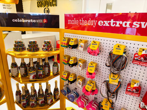M and M candy shop display with colorful jars bottles and branded merchandise on shelves in London, UK showing sweets, gifts and party treats for tourists and shoppers