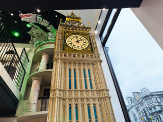 Naklejka premium Large Big Ben model clock tower replica inside a London, UK shop showing detailed architecture and ornate clock face with tourist attraction scale and indoor display