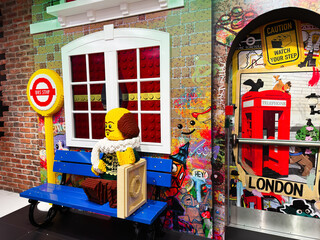 Naklejka premium Colorful Lego bench scene at a London, UK bus stop with red telephone box, graffiti wall and playful brick sculpture