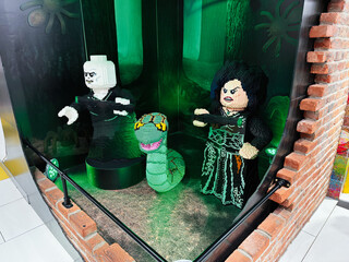 Naklejka premium Lego villain figures display featuring Voldemort Bellatrix and Nagini in a green forest window set at a London UK toy store