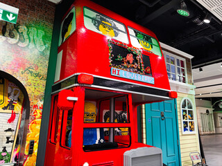 Fototapeta premium Red Lego double decker bus display with smiling minifigure faces in a colorful London UK toy store scene
