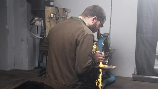Blacksmith sharpening knife in workshop during making