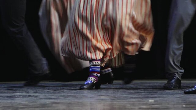 Close-up of dancers&rsquo; feet and flowing skirts during a traditional folk performance on stage, showing movement, rhythm, and cultural costume details.