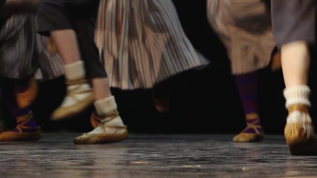 Close-up of dancers' feet in soft leather shoes and white socks performing on a stage, capturing movement, rhythm, and traditional folk dance.