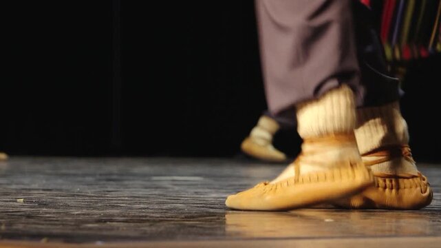 Close-up of dancers' feet in soft leather shoes and white socks performing on a stage, capturing movement, rhythm, and traditional folk dance.