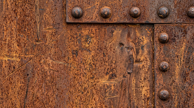 Weathered industrial rusted steel texture with rivets. Heavy-duty rusted orange and brown steel plate texture with industrial rivets and weathered patina.