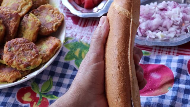 Stuffing Moroccan maakouda sandwich into baguette close-up