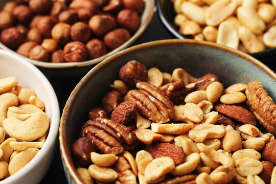 Mixed nuts in ceramic bowls close up. Healthy snack assortment with pecans almonds peanuts and cashews. Organic food for nutrition and dieting. Natural protein rich ingredients