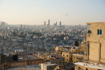 Obraz premium Panoramic skyline of Amman, Jordan, during a colorful sunset with warm golden light illuminating the city