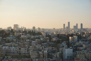 Obraz premium Panoramic skyline of Amman, Jordan, during a colorful sunset with warm golden light illuminating the city