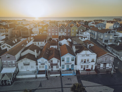 Aerial view of colorful beach huts at sunset along the ocean, Costa Nova, Gafanha da Encarnacao, Aveiro, Portugal.